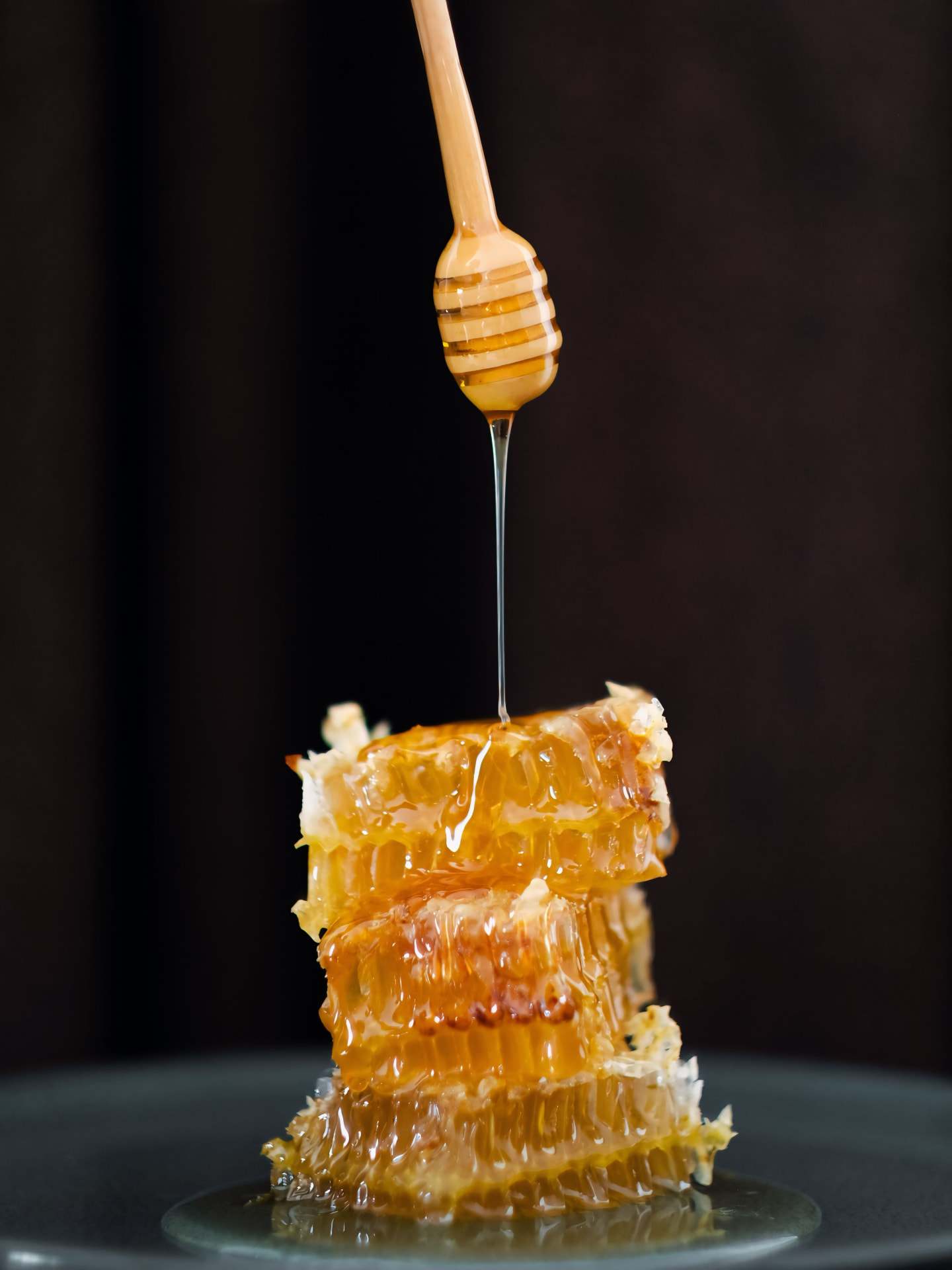 Raw honeycomb with honey drizzled from a wooden dipper